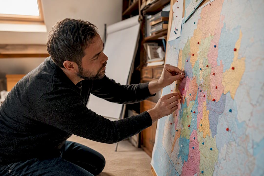 Hands placing service area pins on wall map
